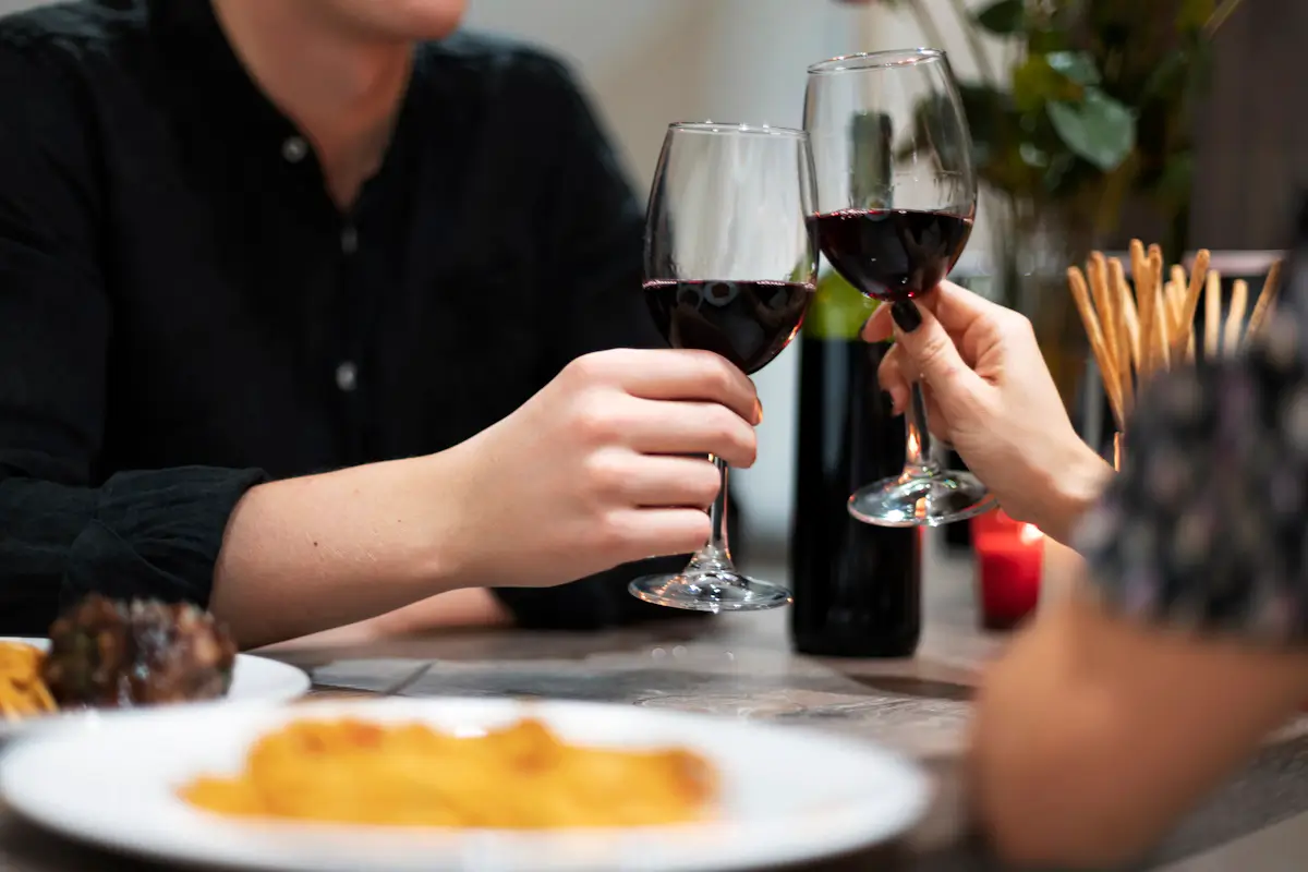 People toasting with red wine at dinner.