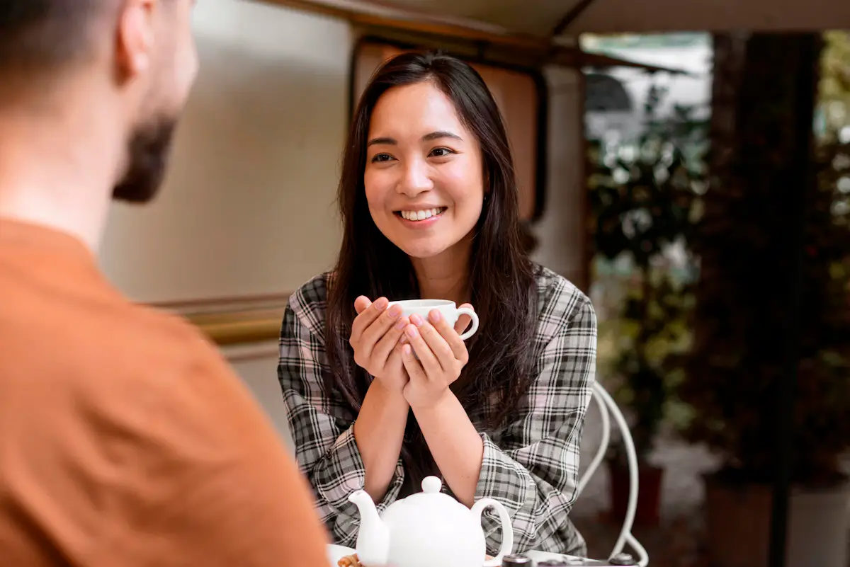 Asian Woman smiling holding cup, casual coffee meeting.
