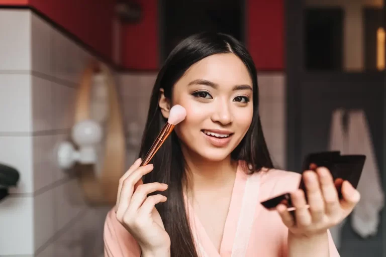 Ladyboy Anwendung Make-up mit schönen dunklen Haaren ist lächelnd