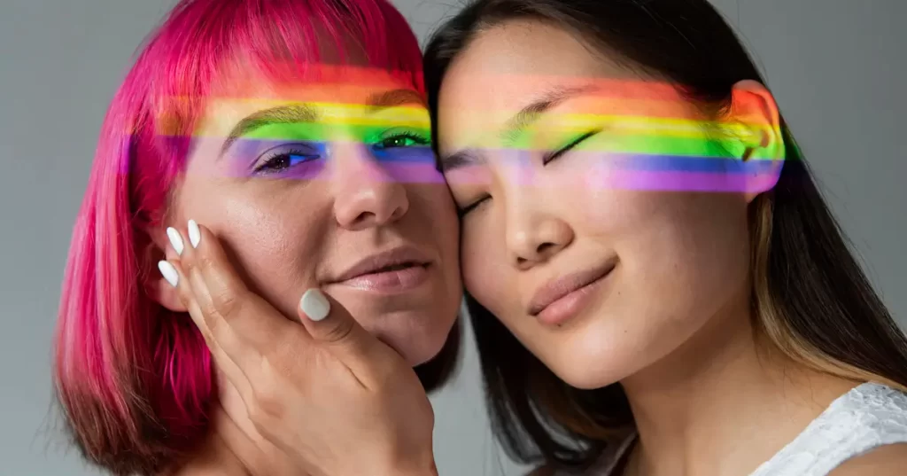 Two women with rainbow light on faces.