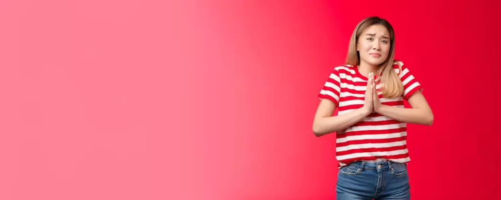 Woman in striped shirt looking doubtful, red background.