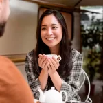 Asian Woman smiling holding cup, casual coffee meeting.
